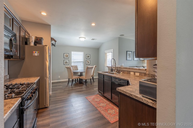 kitchen with recessed lighting, dark wood-style flooring, a sink, black appliances, and dark brown cabinetry