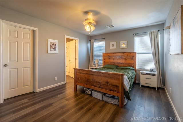 bedroom with dark wood finished floors, baseboards, visible vents, and ensuite bathroom