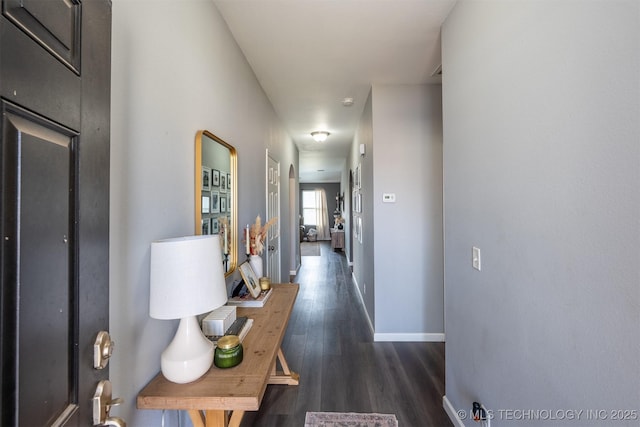 hallway featuring dark wood-type flooring and baseboards