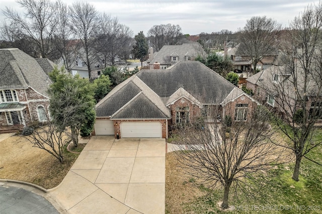 view of front of home with brick siding, driveway, a shingled roof, and a garage