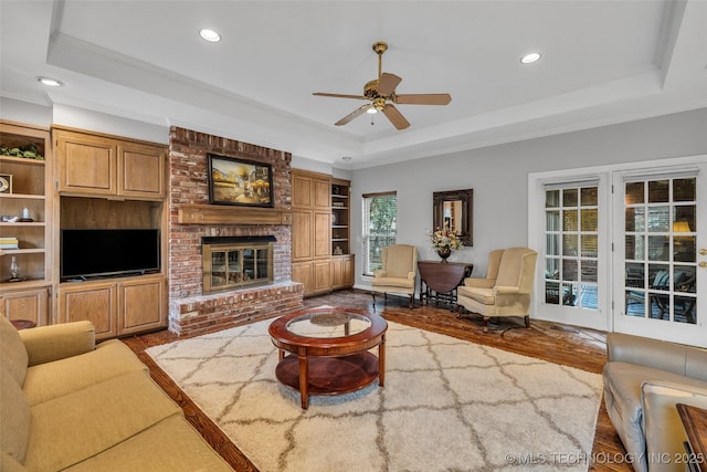 living room featuring a ceiling fan, a tray ceiling, wood finished floors, recessed lighting, and crown molding