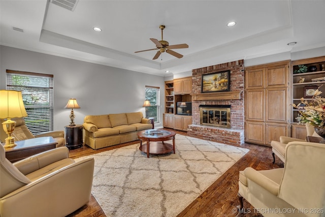 living area featuring visible vents, a healthy amount of sunlight, and a tray ceiling