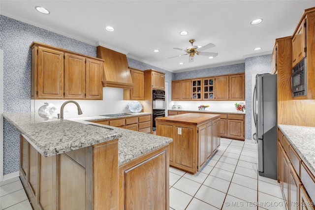 kitchen with black appliances, custom range hood, a center island, a peninsula, and ceiling fan