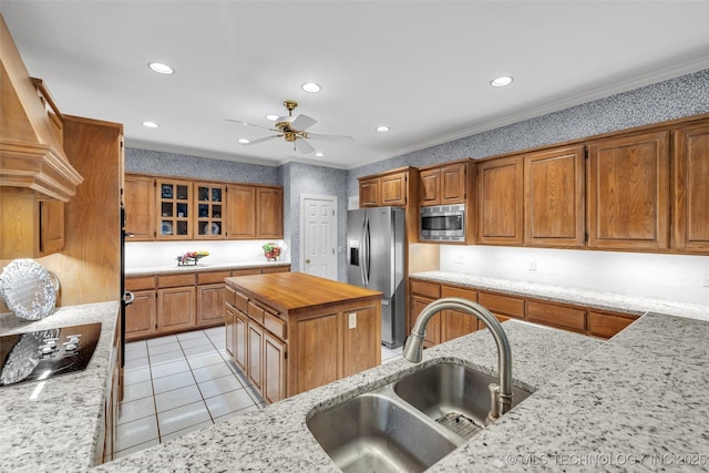 kitchen with a sink, appliances with stainless steel finishes, light tile patterned flooring, light stone countertops, and ceiling fan