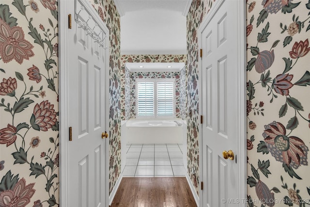 corridor with wood finished floors and wallpapered walls