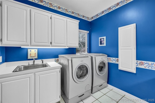 laundry area with a sink, cabinet space, separate washer and dryer, light tile patterned floors, and baseboards