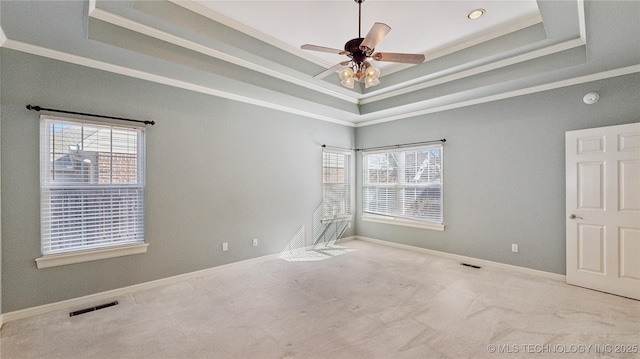 unfurnished room with visible vents, crown molding, baseboards, carpet, and a raised ceiling