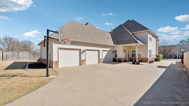 view of side of home featuring concrete driveway, fence, a garage, and roof with shingles