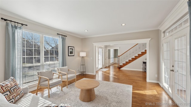 living area featuring crown molding, baseboards, stairway, french doors, and wood finished floors