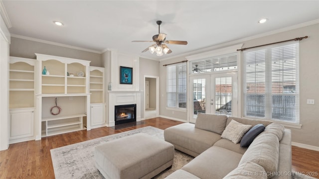 living area with crown molding, a ceiling fan, and wood finished floors