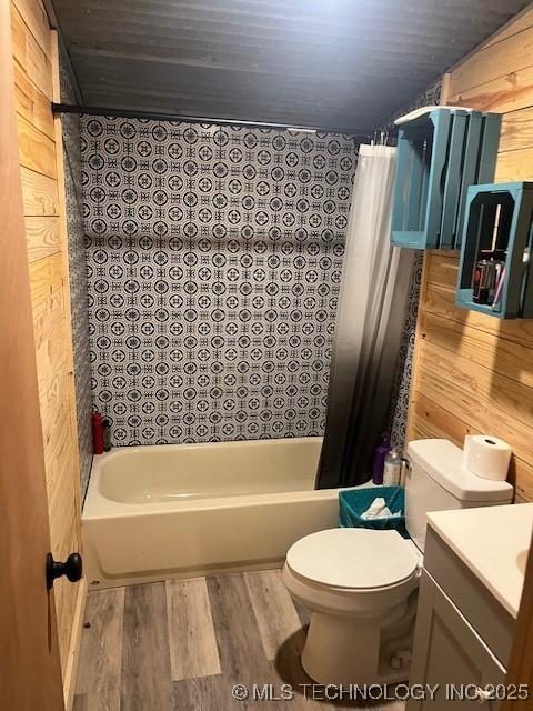 full bath with vanity, wood finished floors, shower / tub combo, wood walls, and toilet