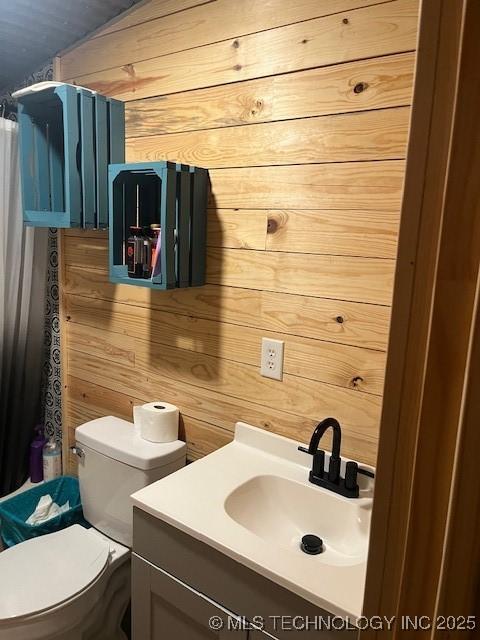 full bath featuring a shower with shower curtain, toilet, wood walls, and vanity