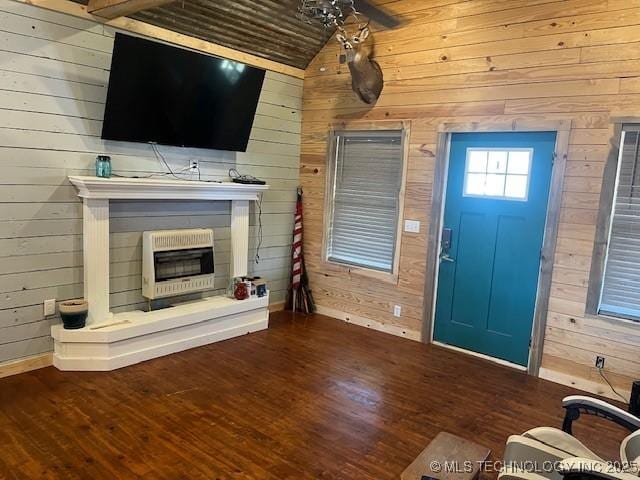 interior space with heating unit, wood finished floors, vaulted ceiling, wood walls, and a glass covered fireplace