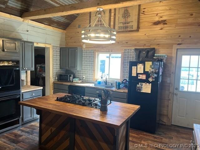kitchen featuring black appliances, wooden walls, plenty of natural light, and wood counters