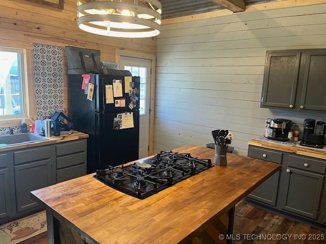 kitchen with wooden walls, wooden counters, gray cabinets, a sink, and black appliances