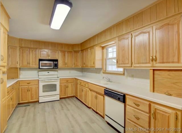 kitchen featuring white appliances, light brown cabinets, light countertops, and a sink