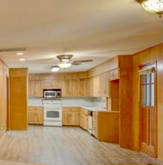 kitchen featuring a ceiling fan, light countertops, electric stove, stainless steel microwave, and light wood-type flooring