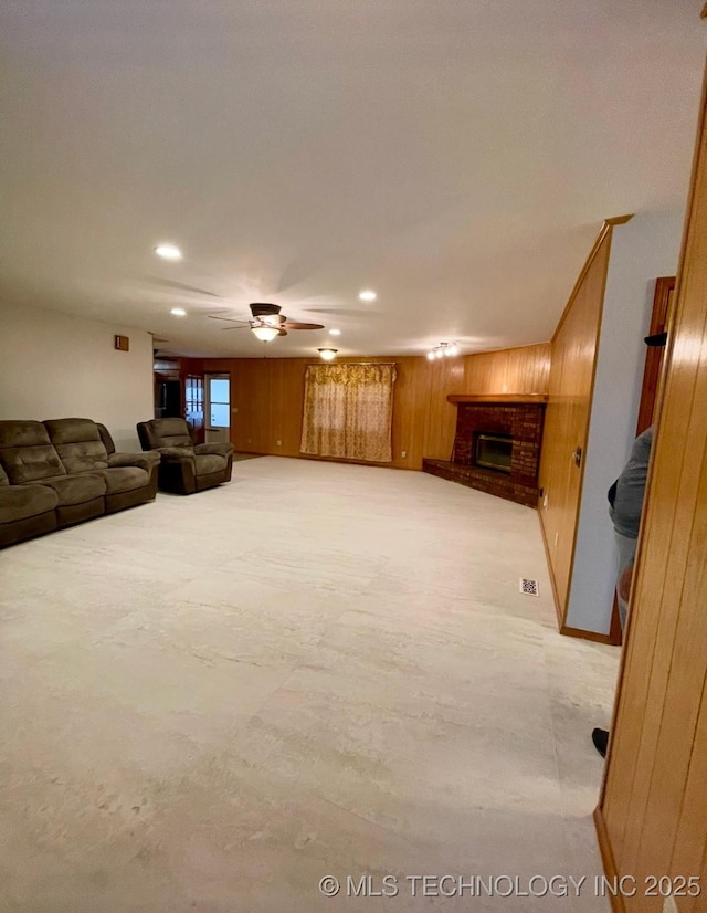 unfurnished living room with recessed lighting, wooden walls, a brick fireplace, and ceiling fan