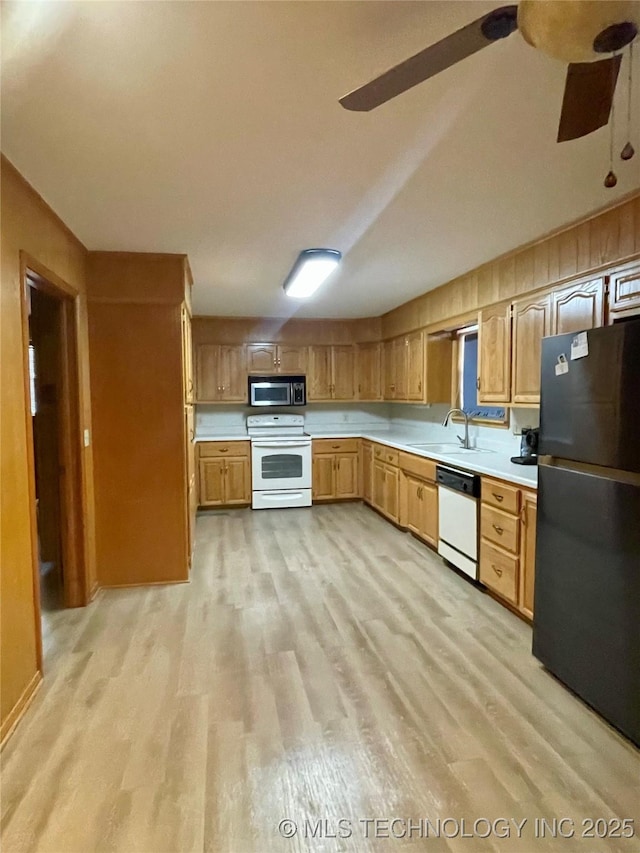 kitchen with white appliances, light countertops, light wood-type flooring, and a sink