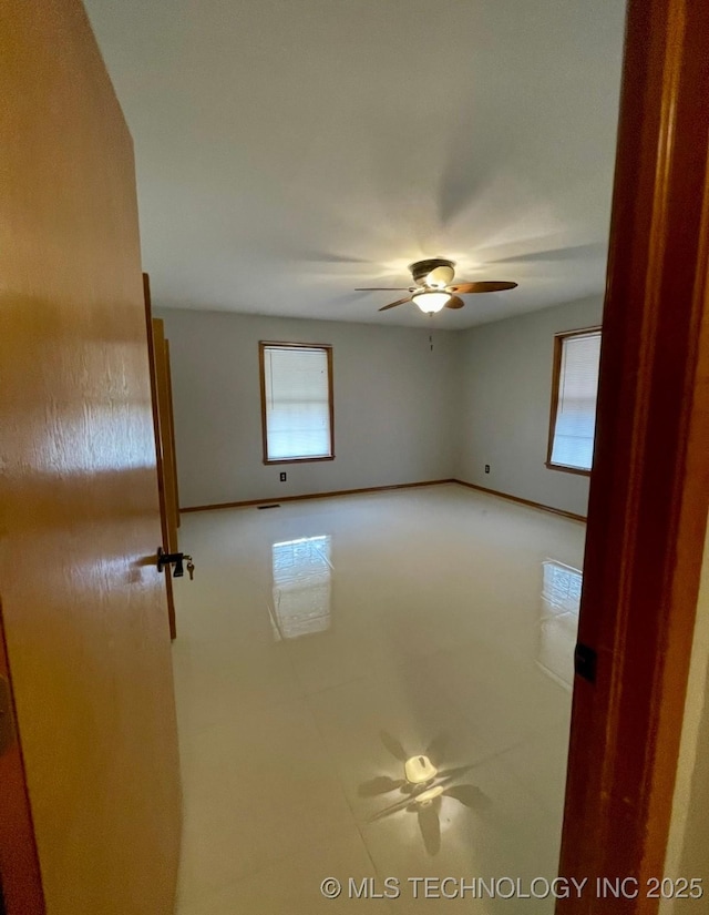 unfurnished room with baseboards and ceiling fan