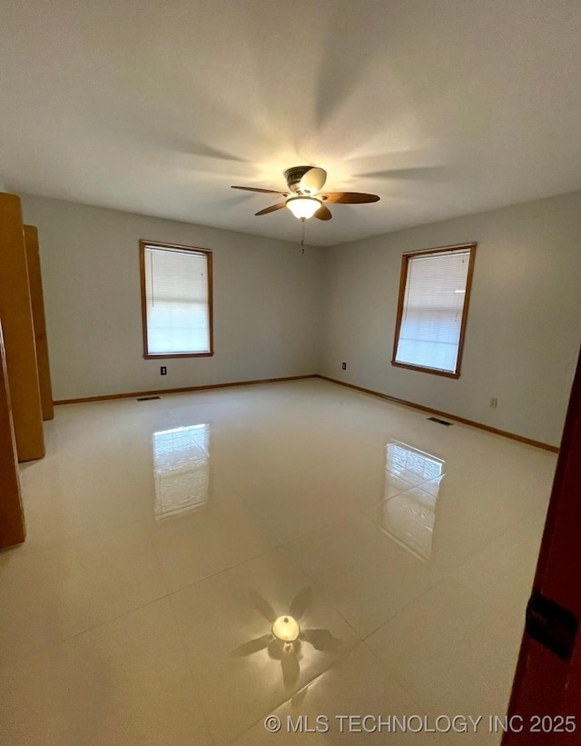 spare room featuring visible vents, baseboards, ceiling fan, and light tile patterned flooring