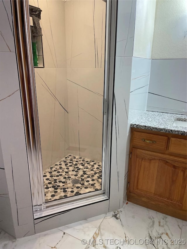 full bath featuring vanity, marble finish floor, and a shower stall