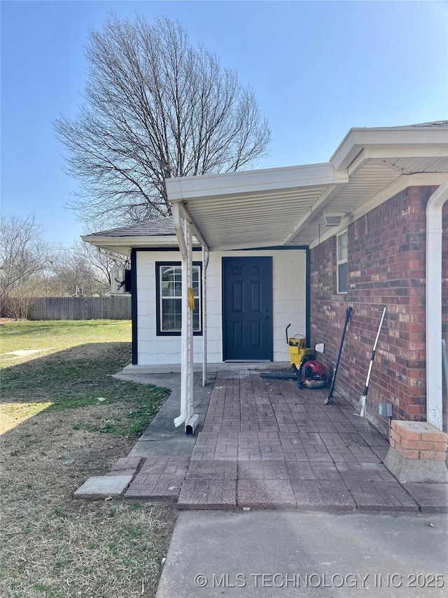 entrance to property featuring a lawn and fence