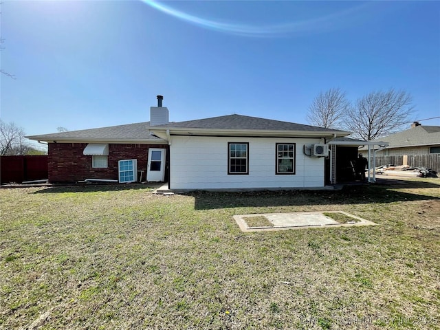 rear view of property with a chimney, a yard, and fence