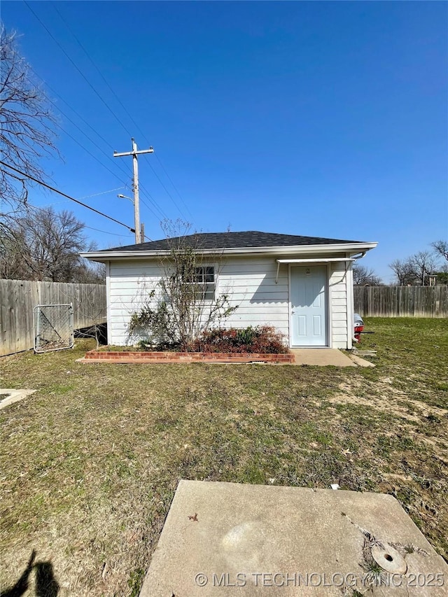 rear view of house featuring a yard and fence