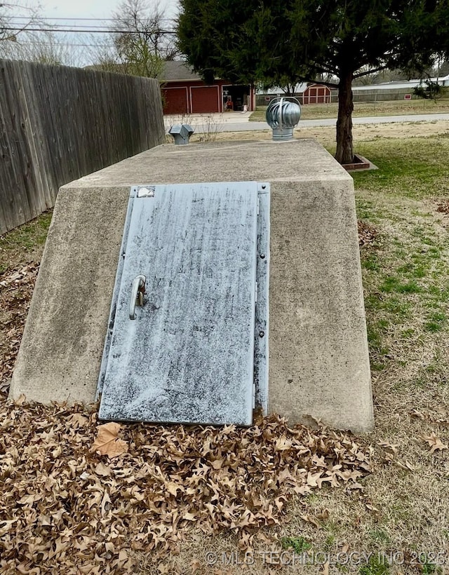 entry to storm shelter featuring a lawn and fence