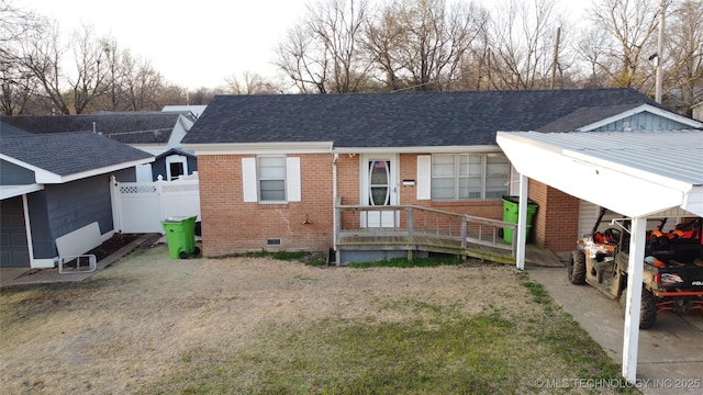 rear view of house with crawl space, brick siding, a shingled roof, and fence