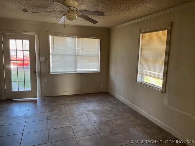 tiled spare room with a ceiling fan, crown molding, a healthy amount of sunlight, and a textured ceiling