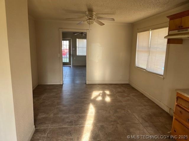 spare room with a textured ceiling, baseboards, and ceiling fan