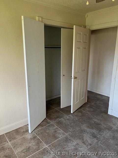 unfurnished bedroom featuring baseboards, crown molding, a closet, and a textured ceiling