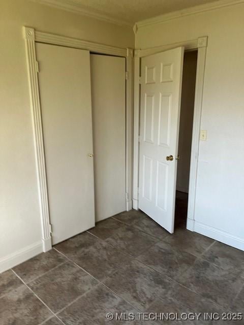 unfurnished bedroom with baseboards, a closet, and crown molding