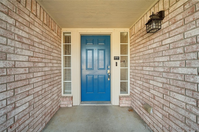 property entrance with brick siding and a porch