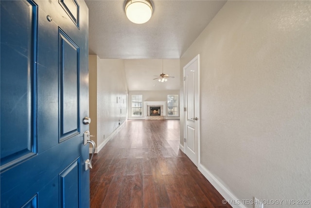 corridor with baseboards, a textured ceiling, and dark wood finished floors