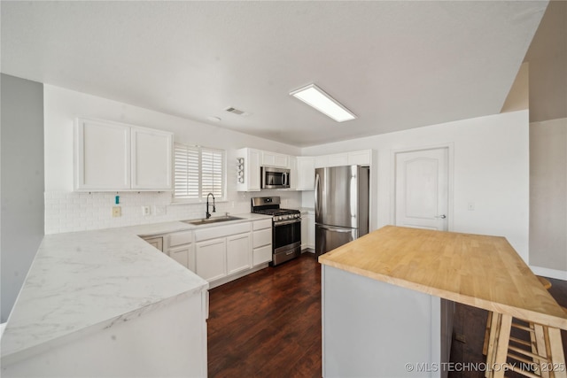 kitchen with dark wood-style flooring, white cabinets, appliances with stainless steel finishes, and a sink