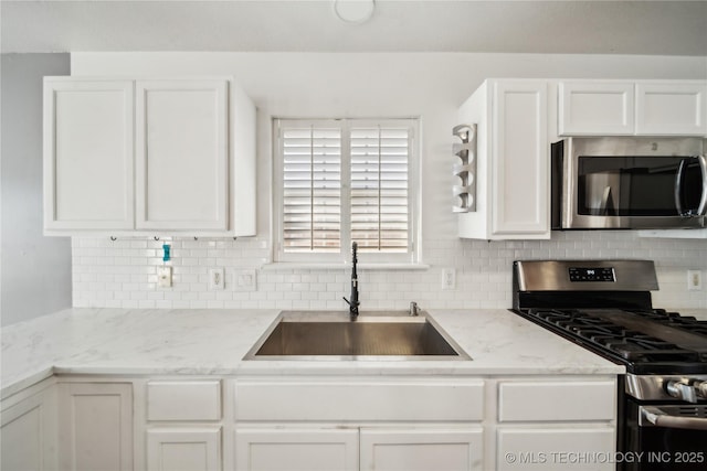 kitchen with a sink, light stone counters, white cabinetry, and stainless steel appliances