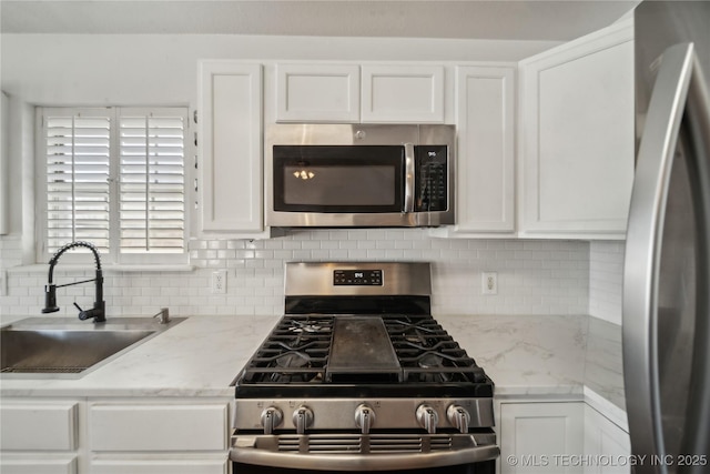 kitchen with a sink, stainless steel appliances, tasteful backsplash, and white cabinets