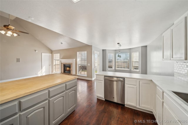 kitchen with ceiling fan, dark wood finished floors, open floor plan, a peninsula, and stainless steel dishwasher