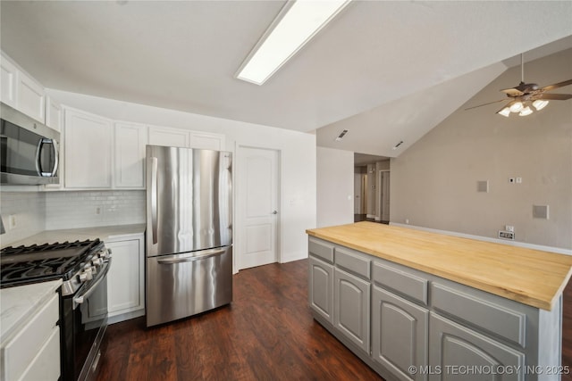 kitchen featuring butcher block countertops, a ceiling fan, dark wood-style floors, appliances with stainless steel finishes, and decorative backsplash