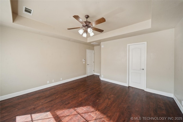 unfurnished room featuring visible vents, wood finished floors, baseboards, a raised ceiling, and ceiling fan