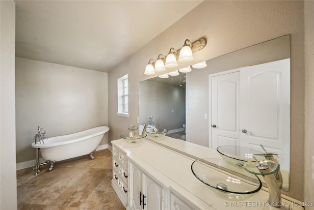 bathroom featuring a soaking tub, vanity, and baseboards