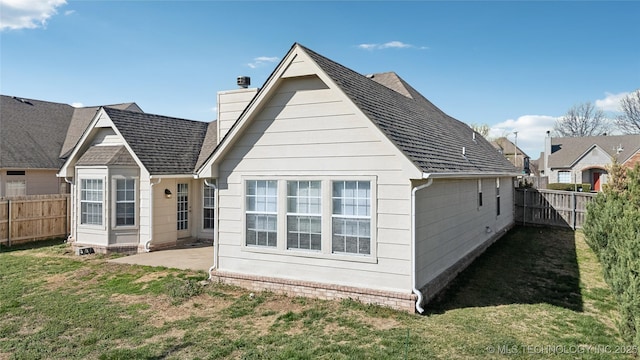 rear view of property featuring a patio area, a yard, a fenced backyard, and a shingled roof