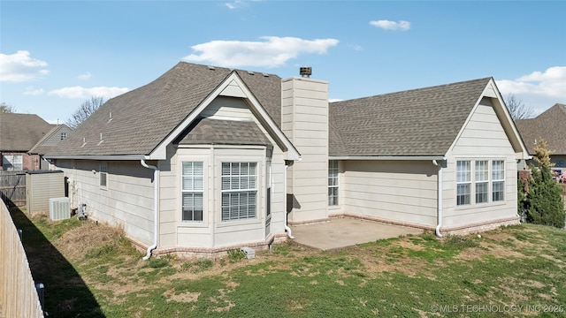 rear view of property with a patio, fence, roof with shingles, a chimney, and a lawn