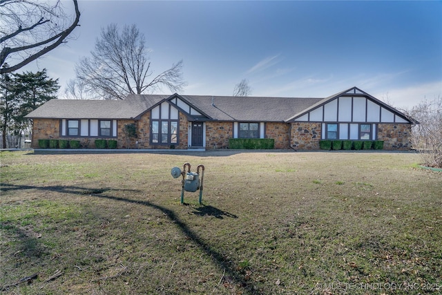 tudor home with stone siding, roof with shingles, and a front yard