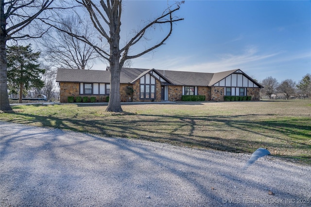 english style home featuring brick siding and a front lawn