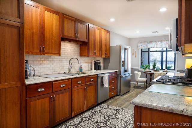 kitchen featuring a sink, stainless steel appliances, brown cabinets, and decorative backsplash