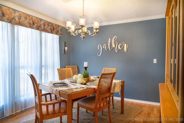 dining area with light wood finished floors, crown molding, baseboards, an inviting chandelier, and a textured ceiling